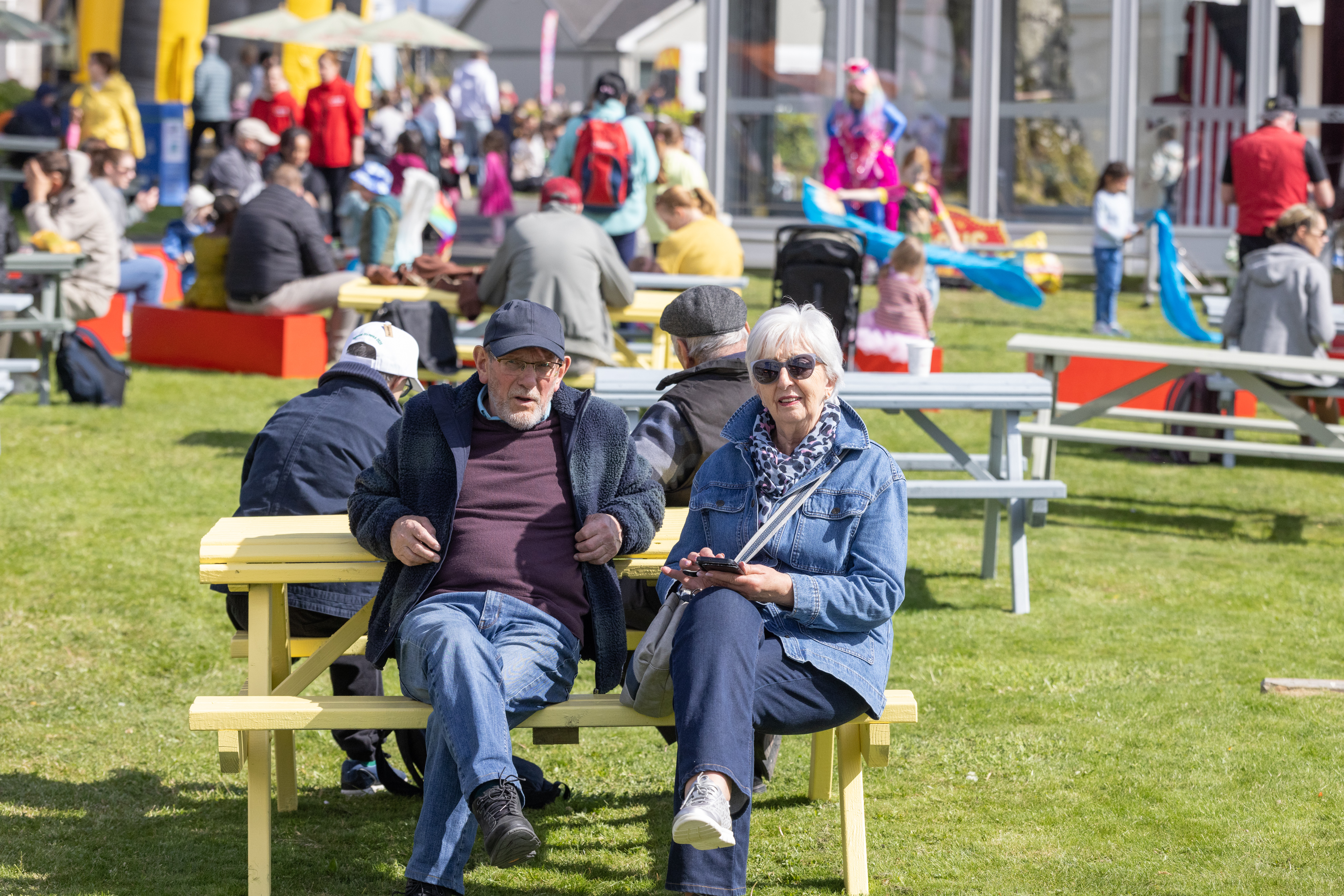 Two people smiling on a picnic bench. 